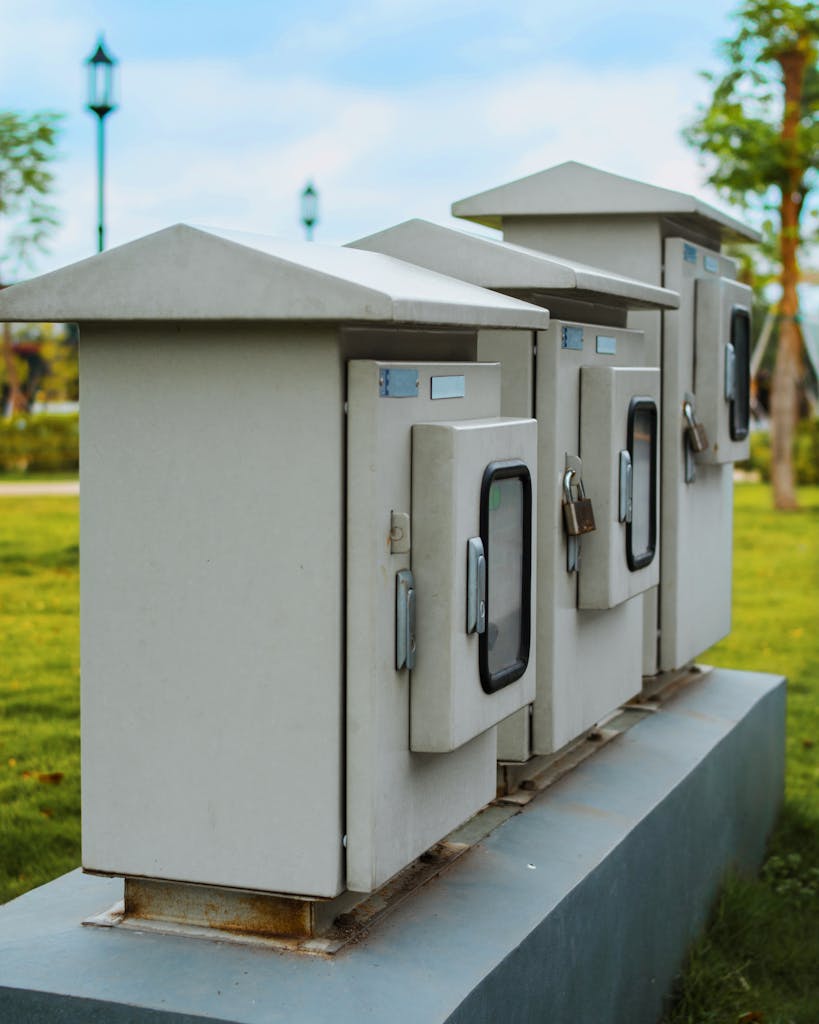 Photo by Raka Miftah Close-up of locked electric boxes outdoors, featuring metal cabinets on a platform.